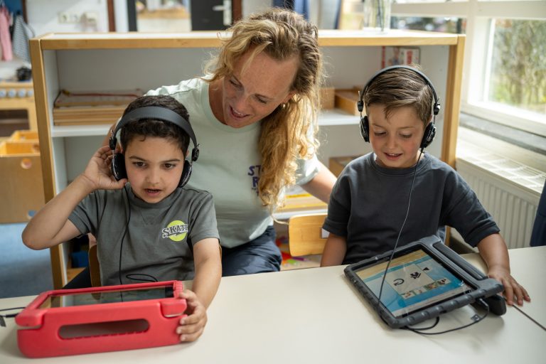 leerkracht met twee leerlingen die spelletjes spelen in LOGO-digitaal