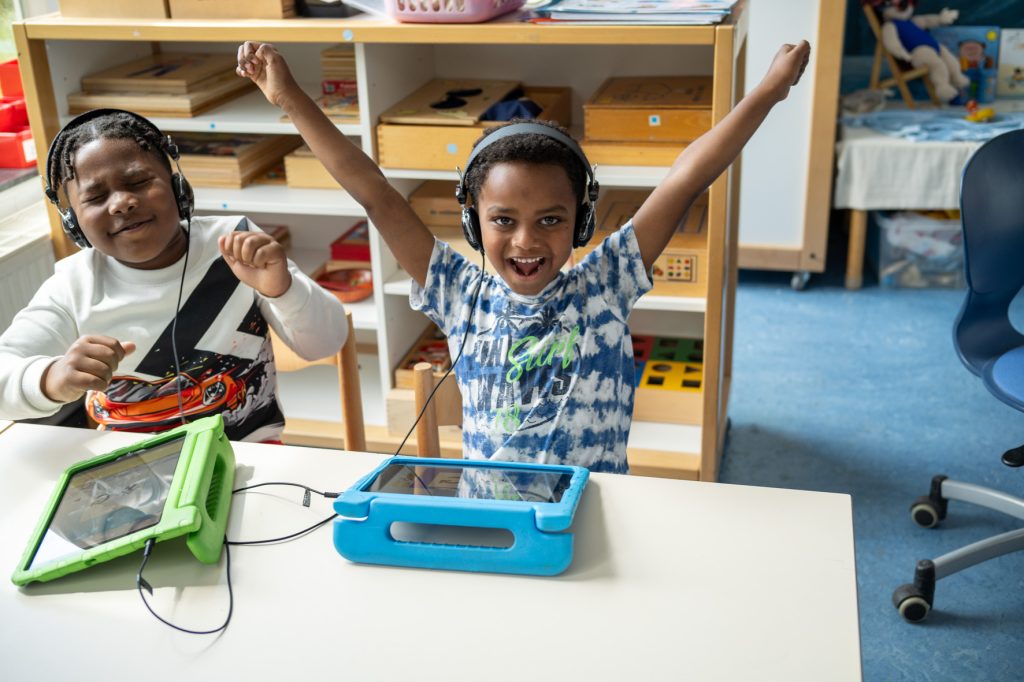 Blije kinderen spelen LOGO-digitaal op een ipad in de klas